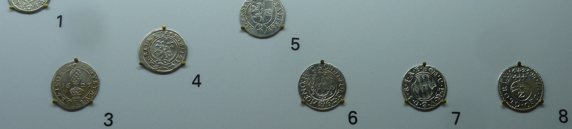 Acht nummerierte, befestigte Münzen
