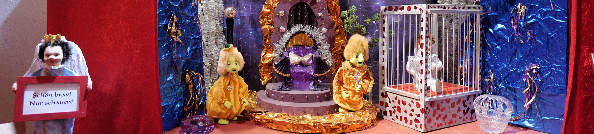 Futuristische Farb- und Kostümgestaltung, Prinz in Käfig soll zur Unterhaltung singen.
