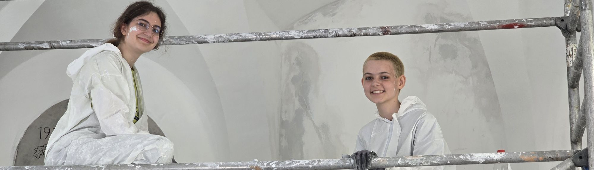 Zwei M&auml;dchen auf einem Gr&uuml;st. Sie pausieren bei einer Arbeit im Kirchengew&ouml;lbe.